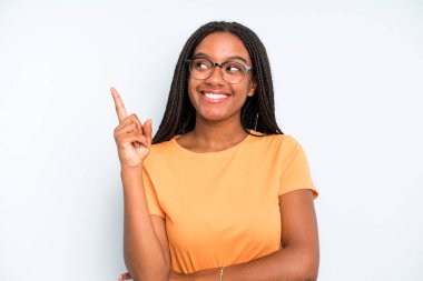 black young adult woman smiling happily and looking sideways, wondering, thinking or having an idea