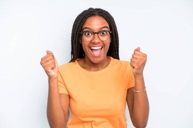 black young adult woman feeling shocked, excited and happy, laughing and celebrating success, saying wow!