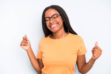 black young adult woman smiling, feeling carefree, relaxed and happy, dancing and listening to music, having fun at a party