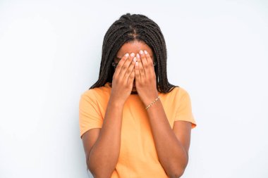 black young adult woman feeling sad, frustrated, nervous and depressed, covering face with both hands, crying