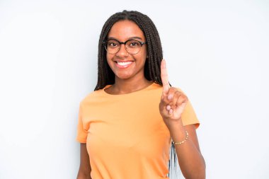 black young adult woman smiling and looking friendly, showing number one or first with hand forward, counting down