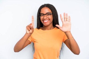 black young adult woman smiling and looking friendly, showing number six or sixth with hand forward, counting down
