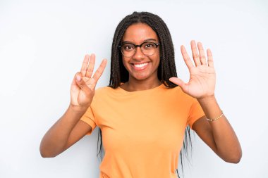 black young adult woman smiling and looking friendly, showing number eight or eighth with hand forward, counting down