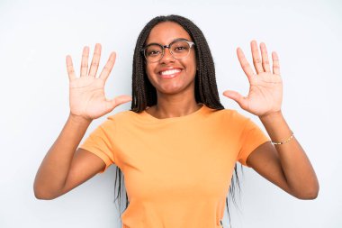 black young adult woman smiling and looking friendly, showing number ten or tenth with hand forward, counting down
