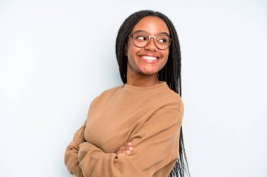 black young adult woman smiling gleefully, feeling happy, satisfied and relaxed, with crossed arms and looking to the side