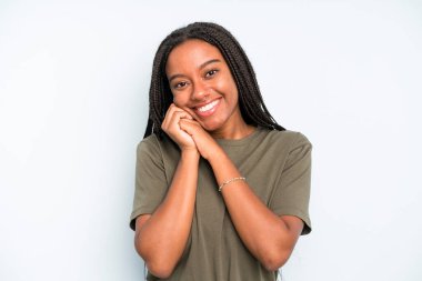 black young adult woman feeling in love and looking cute, adorable and happy, smiling romantically with hands next to face