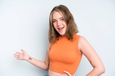 caucasian pretty woman feeling happy and cheerful, smiling and welcoming you, inviting you in with a friendly gesture