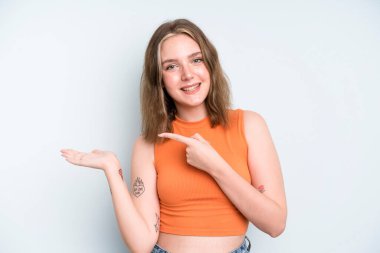 caucasian pretty woman smiling, feeling happy, carefree and satisfied, pointing to concept or idea on copy space on the side