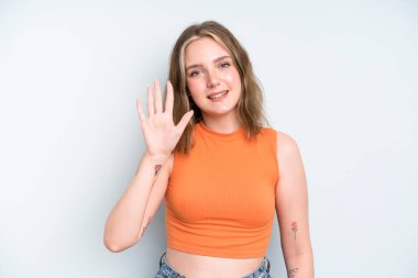 caucasian pretty woman smiling and looking friendly, showing number five or fifth with hand forward, counting down