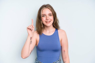 caucasian pretty woman smiling cheerfully and happily, pointing upwards with one hand to copy space
