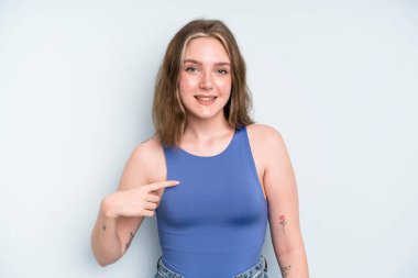 caucasian pretty woman looking happy, proud and surprised, cheerfully pointing to self, feeling confident and lofty