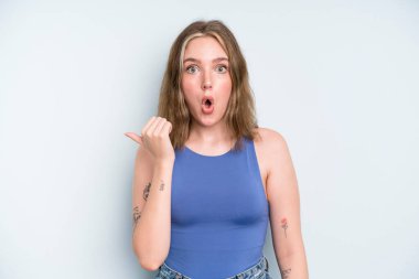 caucasian pretty woman looking astonished in disbelief, pointing at object on the side and saying wow, unbelievable
