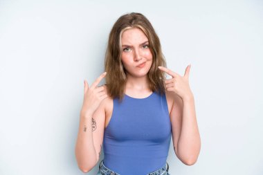 caucasian pretty woman with a bad attitude looking proud and aggressive, pointing upwards or making fun sign with hands