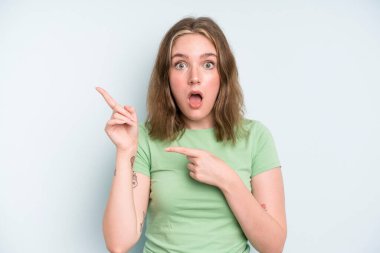 caucasian pretty woman feeling joyful and surprised, smiling with a shocked expression and pointing to the side