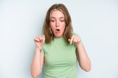 caucasian pretty woman feeling shocked, open-mouthed and amazed, looking and pointing downwards in disbelief and surprise