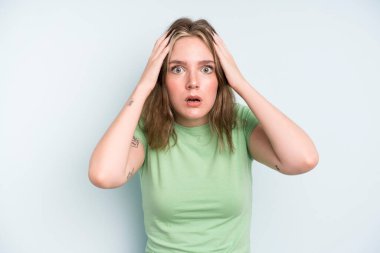 caucasian pretty woman feeling horrified and shocked, raising hands to head and panicking at a mistake