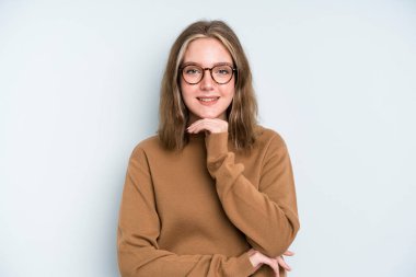 caucasian pretty woman looking happy and smiling with hand on chin, wondering or asking a question, comparing options