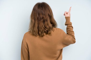 caucasian pretty woman standing and pointing to object on copy space, rear view
