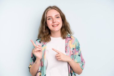 caucasian pretty woman smiling happily and pointing to side and upwards with both hands showing object in copy space