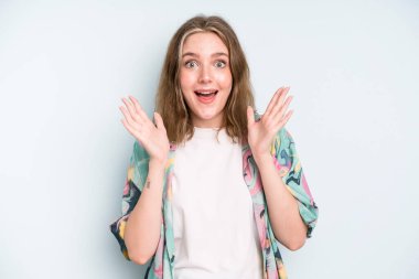 caucasian pretty woman looking happy and excited, shocked with an unexpected surprise with both hands open next to face
