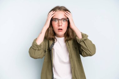 caucasian pretty woman feeling horrified and shocked, raising hands to head and panicking at a mistake
