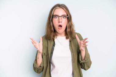caucasian pretty woman feeling extremely shocked and surprised, anxious and panicking, with a stressed and horrified look