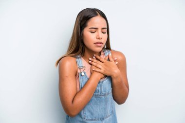hispanic latin pretty woman looking sad, hurt and heartbroken, holding both hands close to heart, crying and feeling depressed