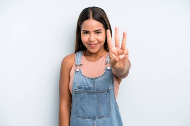 hispanic latin pretty woman smiling and looking friendly, showing number three or third with hand forward, counting down