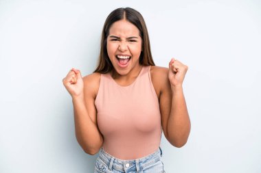 hispanic latin pretty woman looking extremely happy and surprised, celebrating success, shouting and jumping
