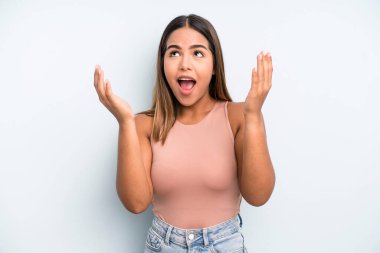 hispanic latin pretty woman feeling happy, amazed, lucky and surprised, celebrating victory with both hands up in the air