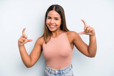 hispanic latin pretty woman framing or outlining own smile with both hands, looking positive and happy, wellness concept
