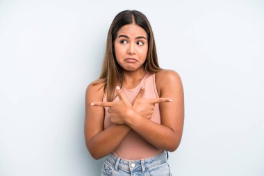 hispanic latin pretty woman looking puzzled and confused, insecure and pointing in opposite directions with doubts