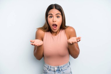 hispanic latin pretty woman open-mouthed and amazed, shocked and astonished with an unbelievable surprise