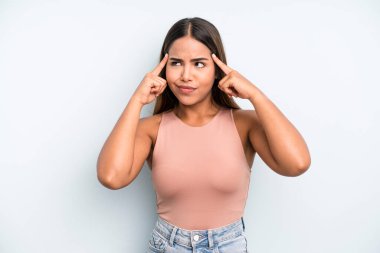 hispanic latin pretty woman looking concentrated and thinking hard on an idea, imagining a solution to a challenge or problem