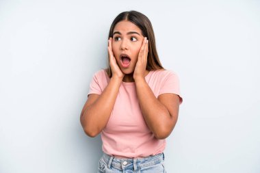 hispanic latin pretty woman feeling happy, excited and surprised, looking to the side with both hands on face