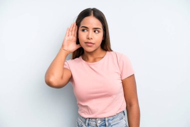 hispanic latin pretty woman looking serious and curious, listening, trying to hear a secret conversation or gossip, eavesdropping