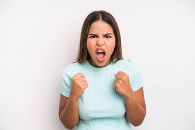 hispanic latin pretty woman shouting aggressively with annoyed, frustrated, angry look and tight fists, feeling furious