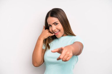 hispanic latin pretty woman smiling cheerfully and pointing to camera while making a call you later gesture, talking on phone