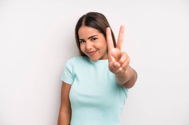 hispanic latin pretty woman smiling and looking friendly, showing number two or second with hand forward, counting down
