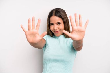 hispanic latin pretty woman smiling and looking friendly, showing number ten or tenth with hand forward, counting down