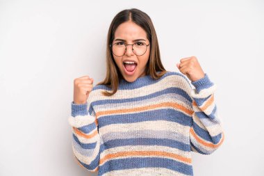 hispanic latin pretty woman feeling happy, surprised and proud, shouting and celebrating success with a big smile