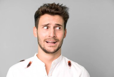 Hamamböcekleriyle izole edilmiş genç yakışıklı adam.