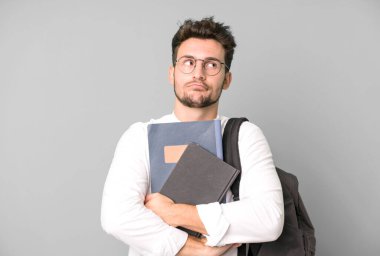 Bir çanta ve kitapla izole edilmiş genç yakışıklı bir adam. Üniversite öğrencisi konsepti