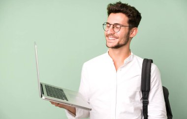 Genç ve yakışıklı bir adam dizüstü bilgisayarla izole edilmiş. Üniversite öğrencisi konsepti