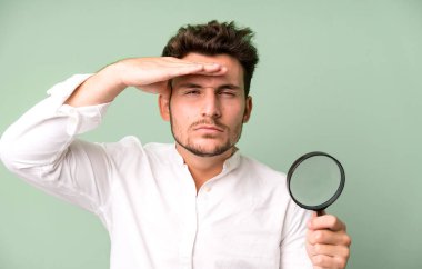 Büyüteçle genç ve yakışıklı bir adam. Ara ya da bul konsepti