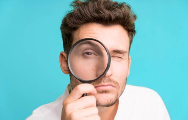 Büyüteçle genç ve yakışıklı bir adam. Ara ya da bul konsepti