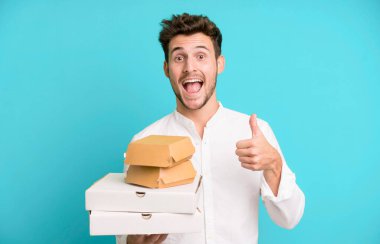 Fast food ile izole edilmiş genç yakışıklı adam kutuları taklit ediyor. teslimat ve paket konsepti