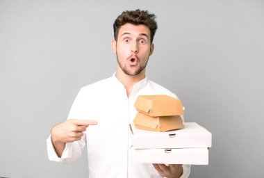 Fast food ile izole edilmiş genç yakışıklı adam kutuları taklit ediyor. teslimat ve paket konsepti