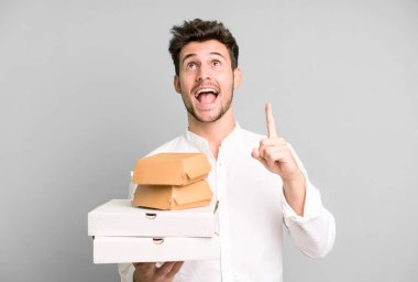 Fast food ile izole edilmiş genç yakışıklı adam kutuları taklit ediyor. teslimat ve paket konsepti