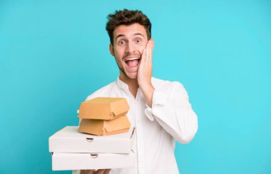 Fast food ile izole edilmiş genç yakışıklı adam kutuları taklit ediyor. teslimat ve paket konsepti